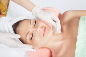 med spa professional in gloves applying skin treatment to face of female patient
